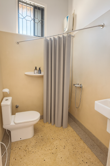 Badezimmer mit Toilette, Waschbecken und Duschvorhang an der Wand.