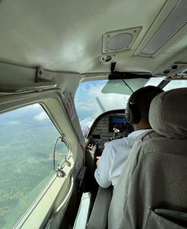 Pilot steuert ein Flugzeug über grüne Landschaften. Blick aus dem Cockpit.