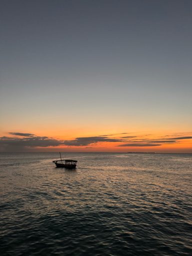 Ein Boot schwimmt ruhig auf dem Wasser unter einem farbenprächtigen Sonnenuntergang.