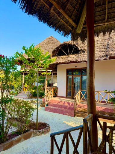 Tropisches Resort mit strohgedeckten Hütten und grünen Pflanzen.